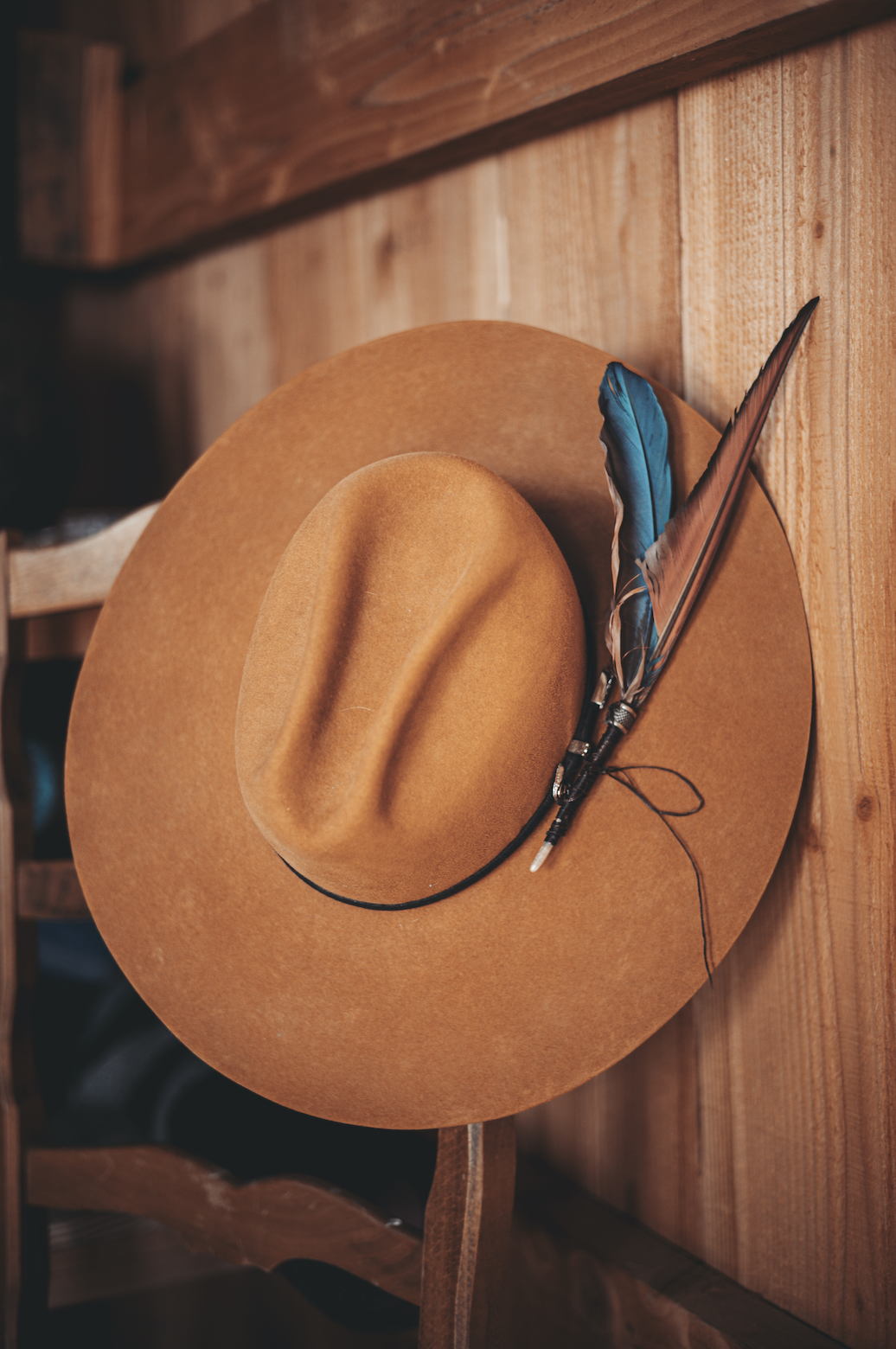 Chapeau de cowgirl orné d'une plume, accroché au bois du ranch